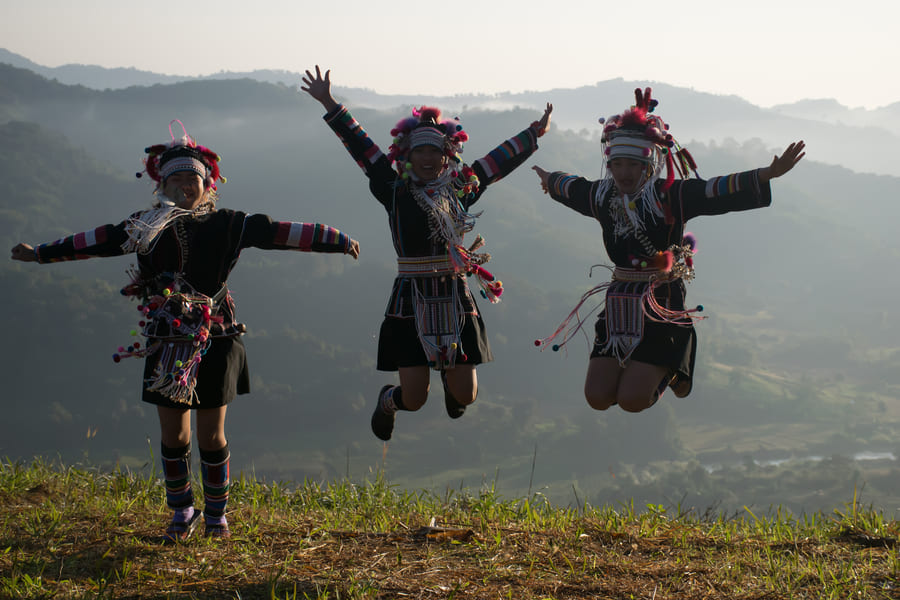 Tres personas chinas saltando con montañas de fondo